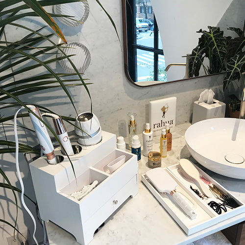 Range of rahua products with other hair essential tools placed near a basin and mirror at NYC flagship store of detox market