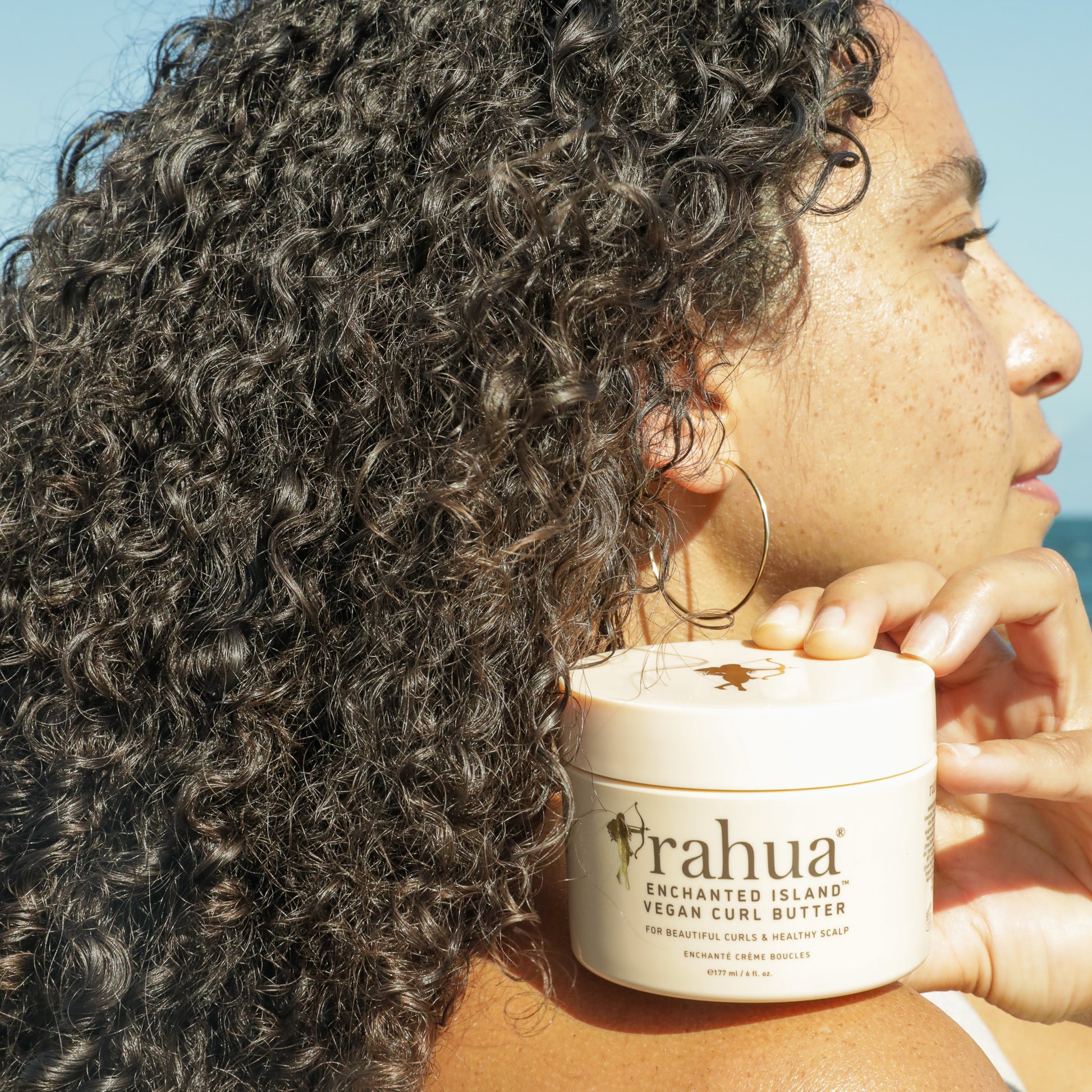 Model with curly hair holding Vegan Curl Butter