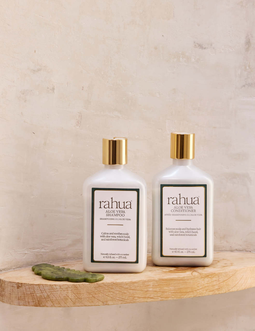 Two bottles of rahua hair care products on a wooden surface with a neutral background