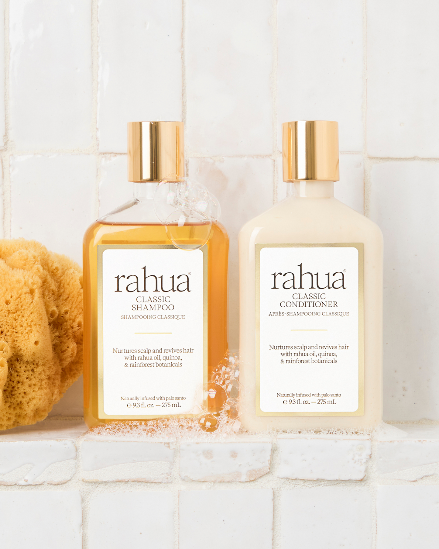 Two bottles of rahua shampoo and conditioner on a white surface with a tiled wall background.|variant:93-oz