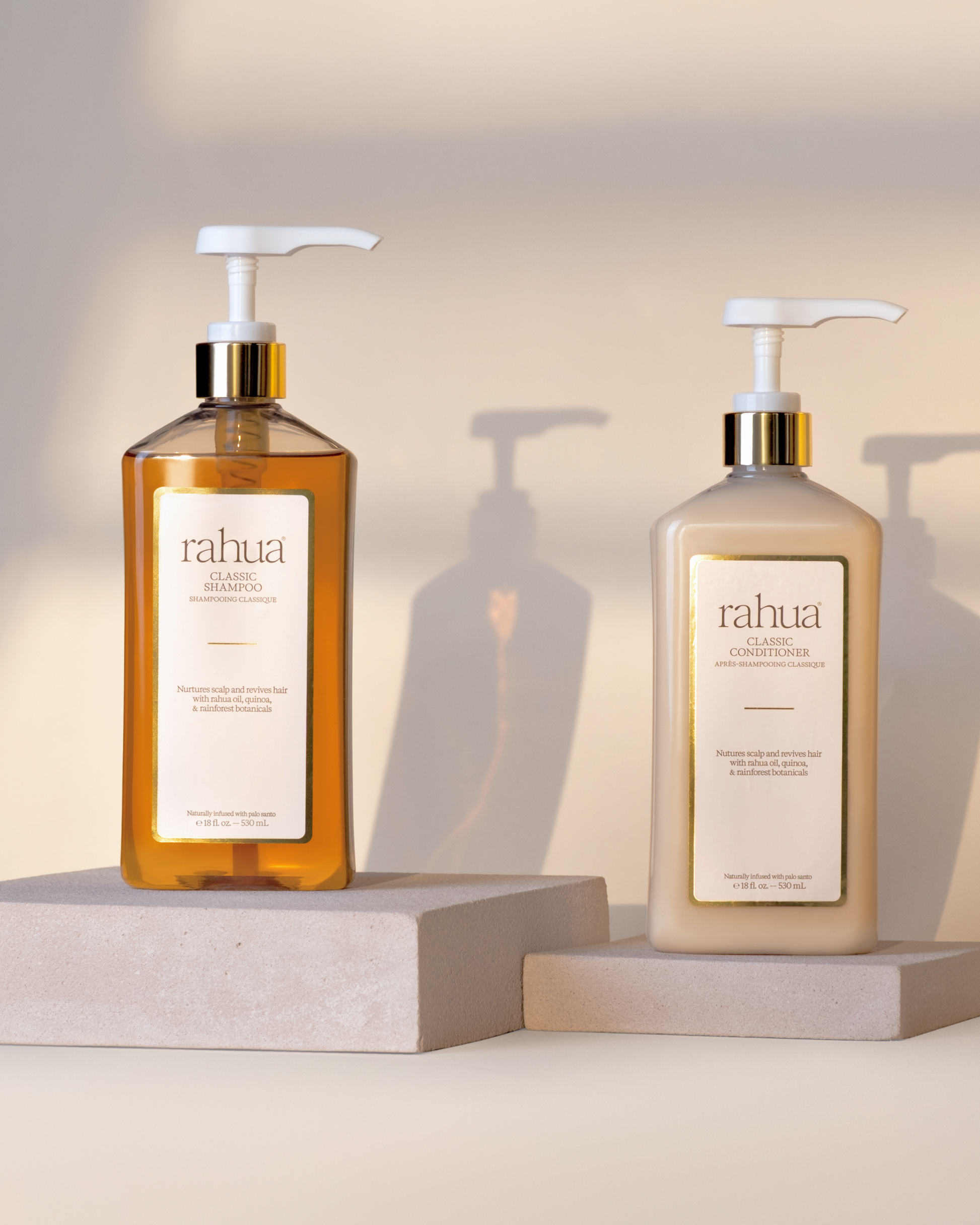 Two bottles of rahua shampoo and conditioner on a neutral background|variant:16-oz