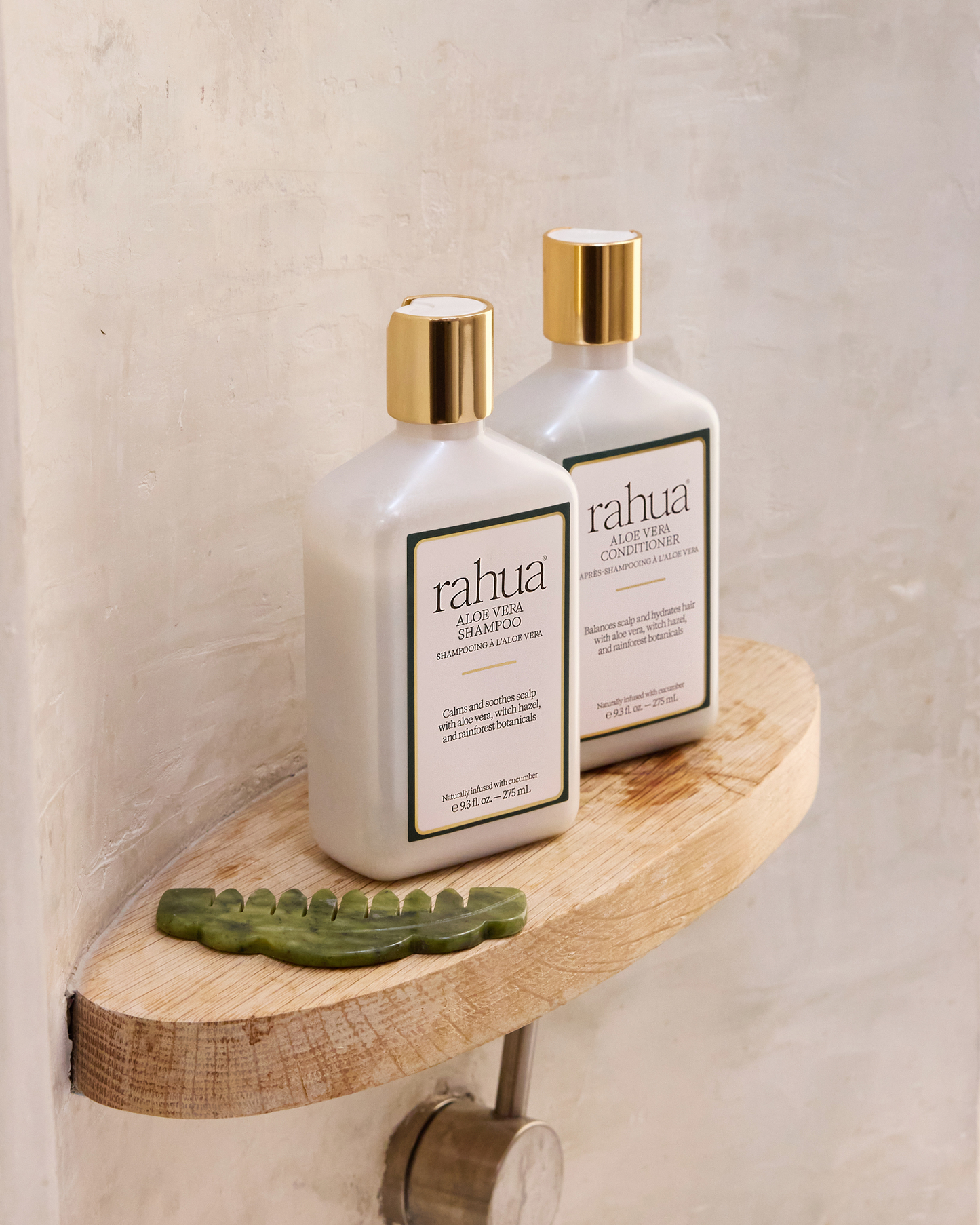 Two bottles of rahua shampoo on a wooden shelf against a neutral wall.