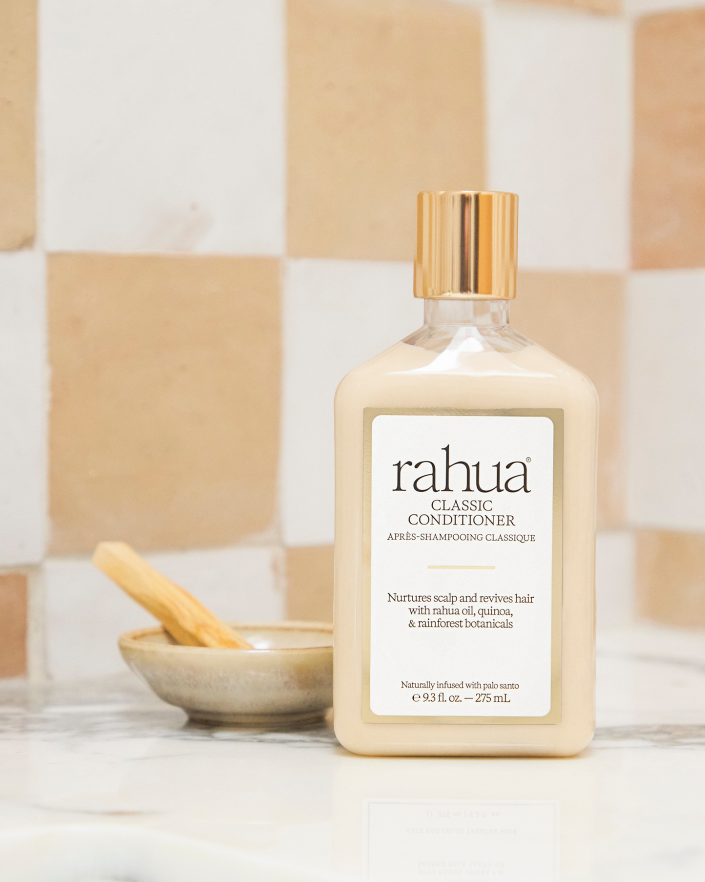 Bottle of rahua classic conditioner on a checkered tile background with a ceramic dish with a stick of palo santo wood incense|variant:93-oz
