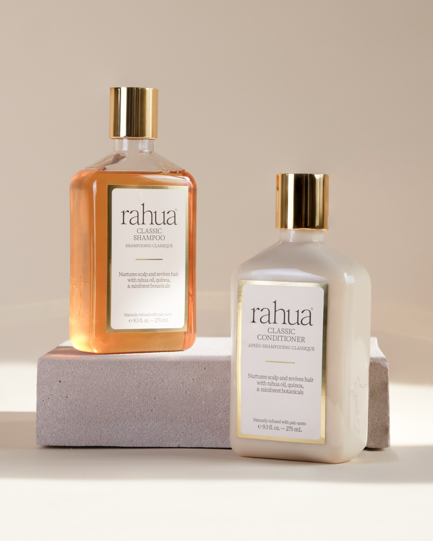 Two bottles of rahua hair care products classic shampoo and classic conditioner on a neutral background sitting on a flat stone|variant:93-oz