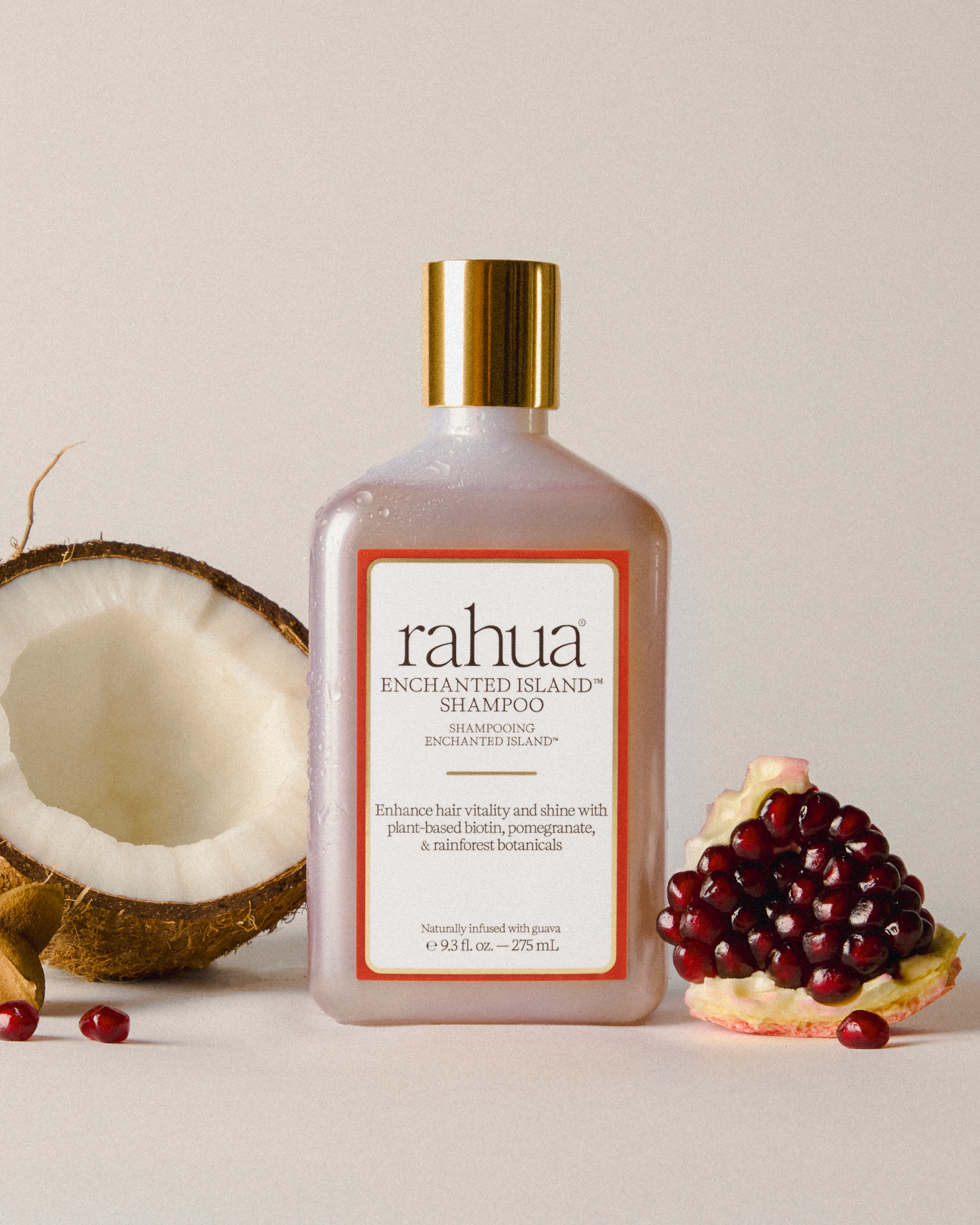 Rahua shampoo of enchanted island shampoo bottle with a coconut and pomegranate on a neutral background|variant:93-oz