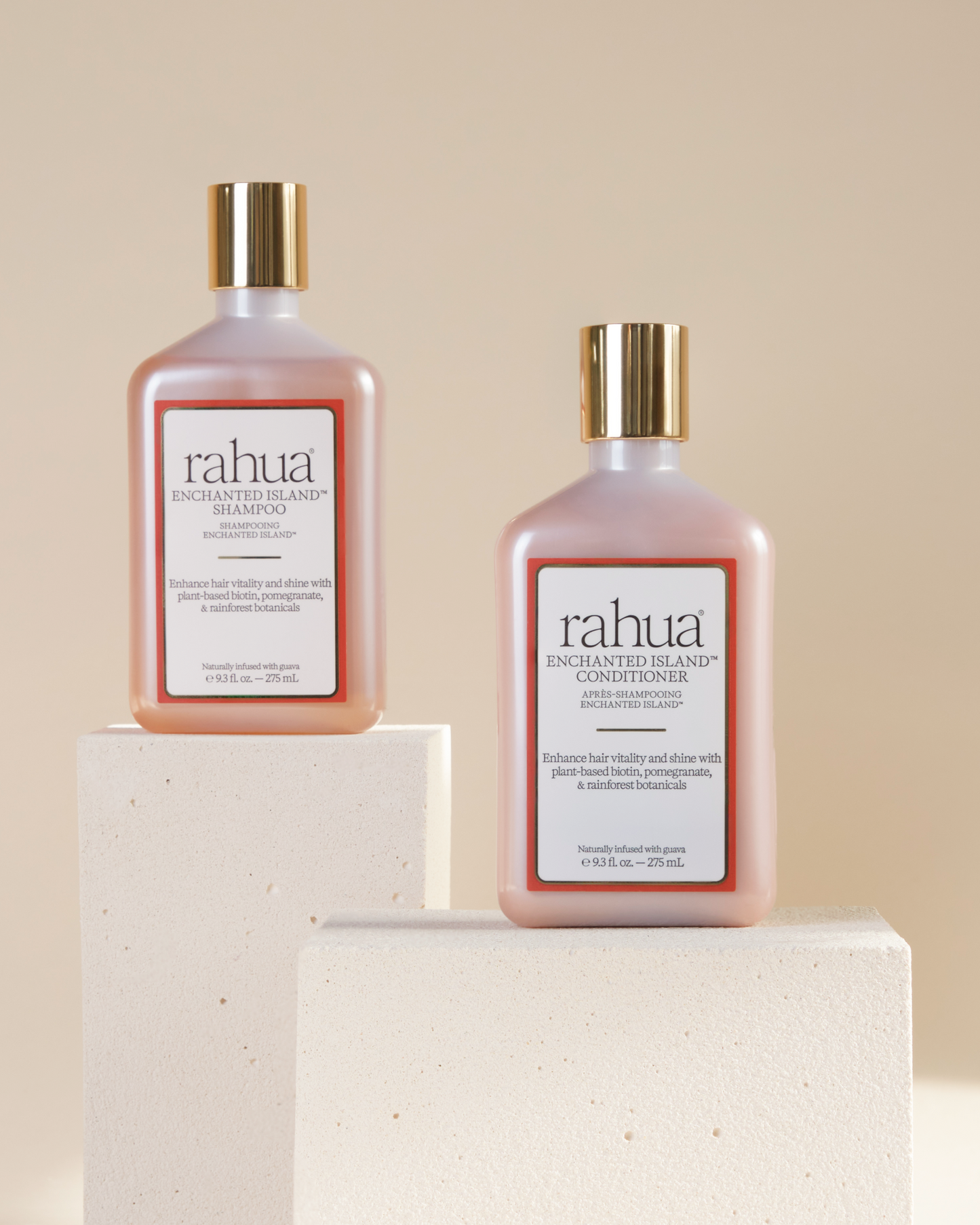 Two bottles of rahua enchanted island shampoo and enchanted island conditioner on a beige background sitting on two off white stone slabs|variant:93-oz