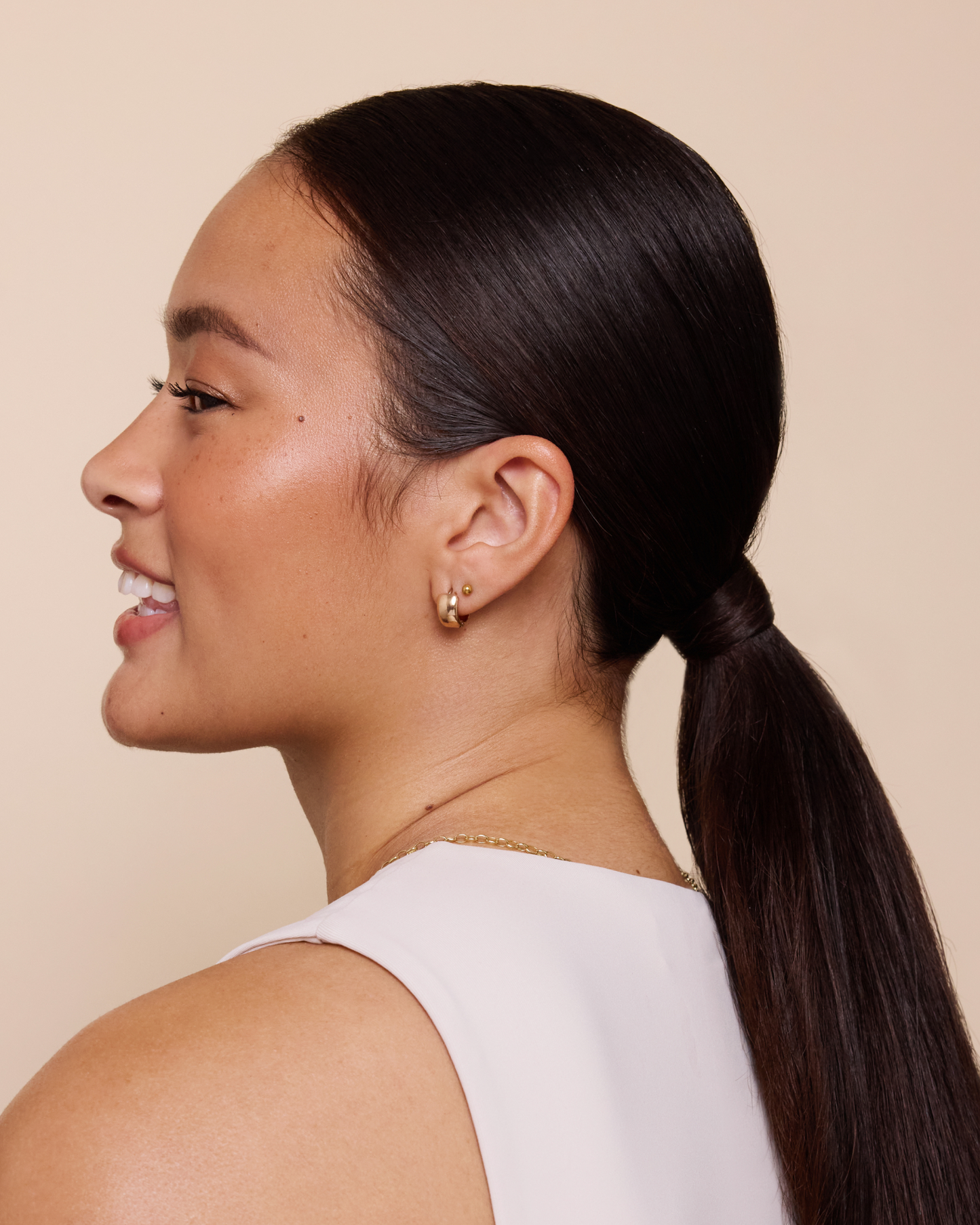 model with straight shiny dark hair in a sleek low ponytail looking to the left|variant:93-oz