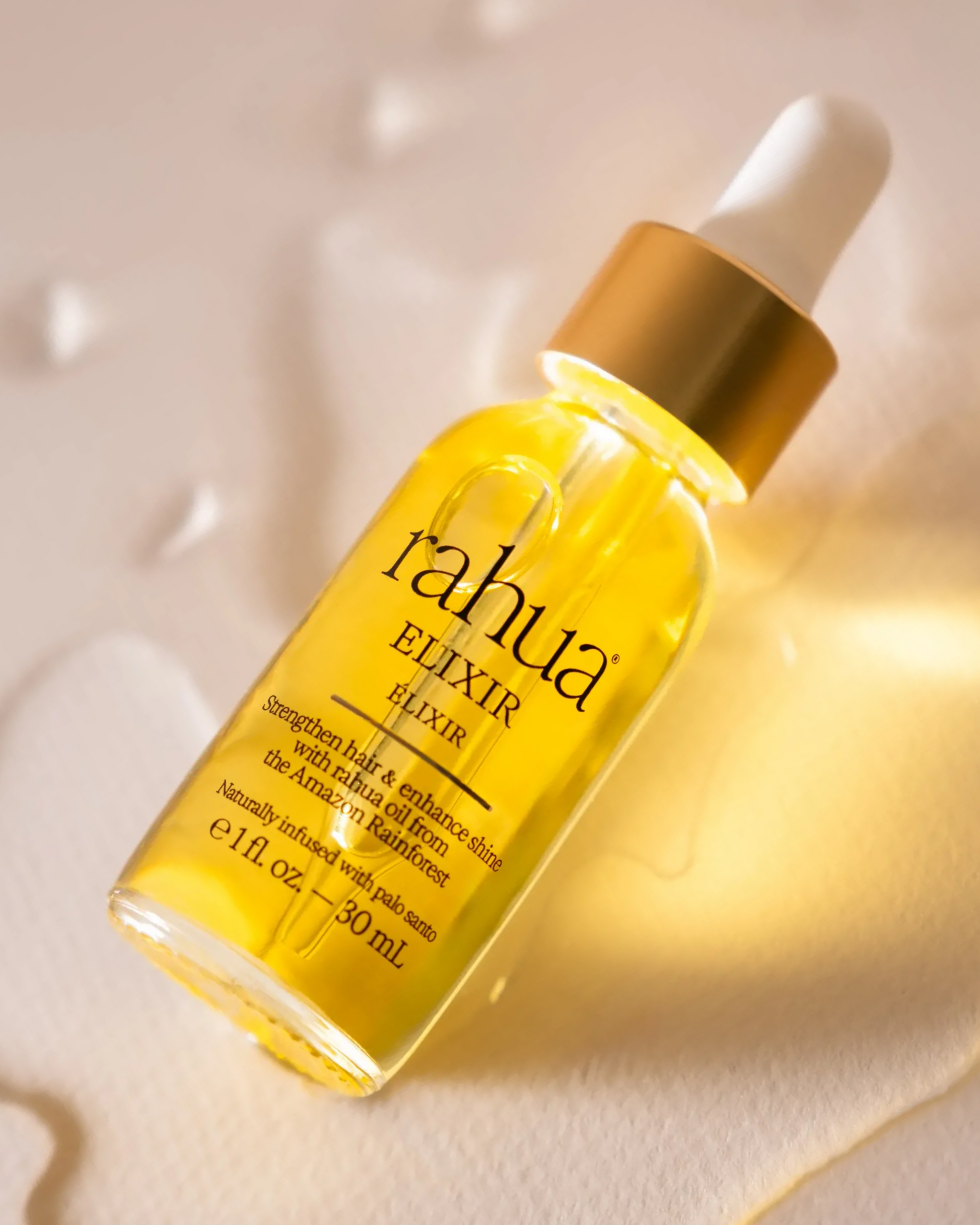 Yellow bottle of rahua elixir on a light background|variant:1-oz