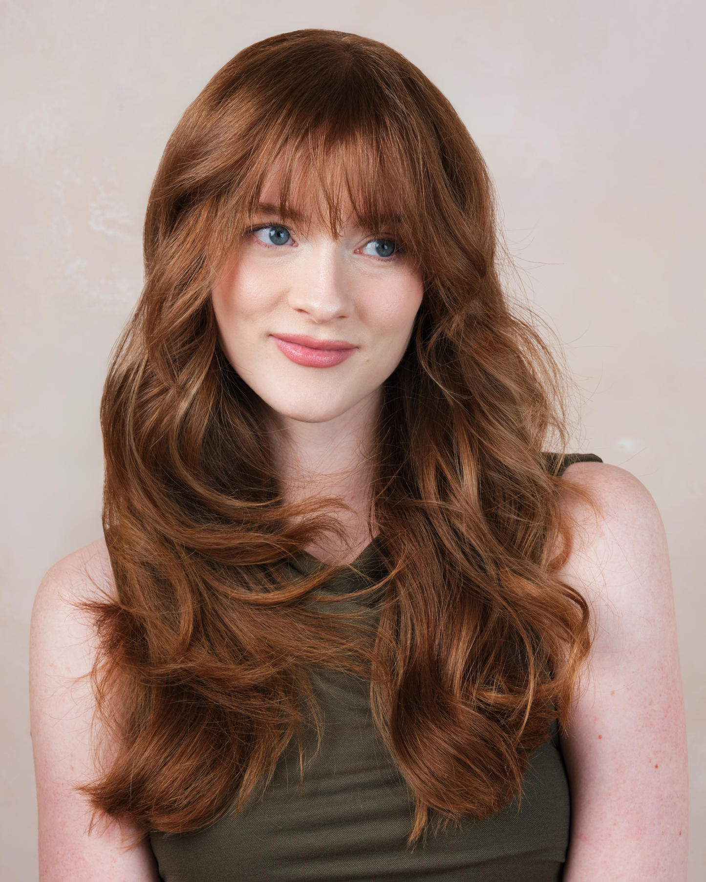 Woman with long wavy brown hair and bangs against a plain background|variant:65-oz