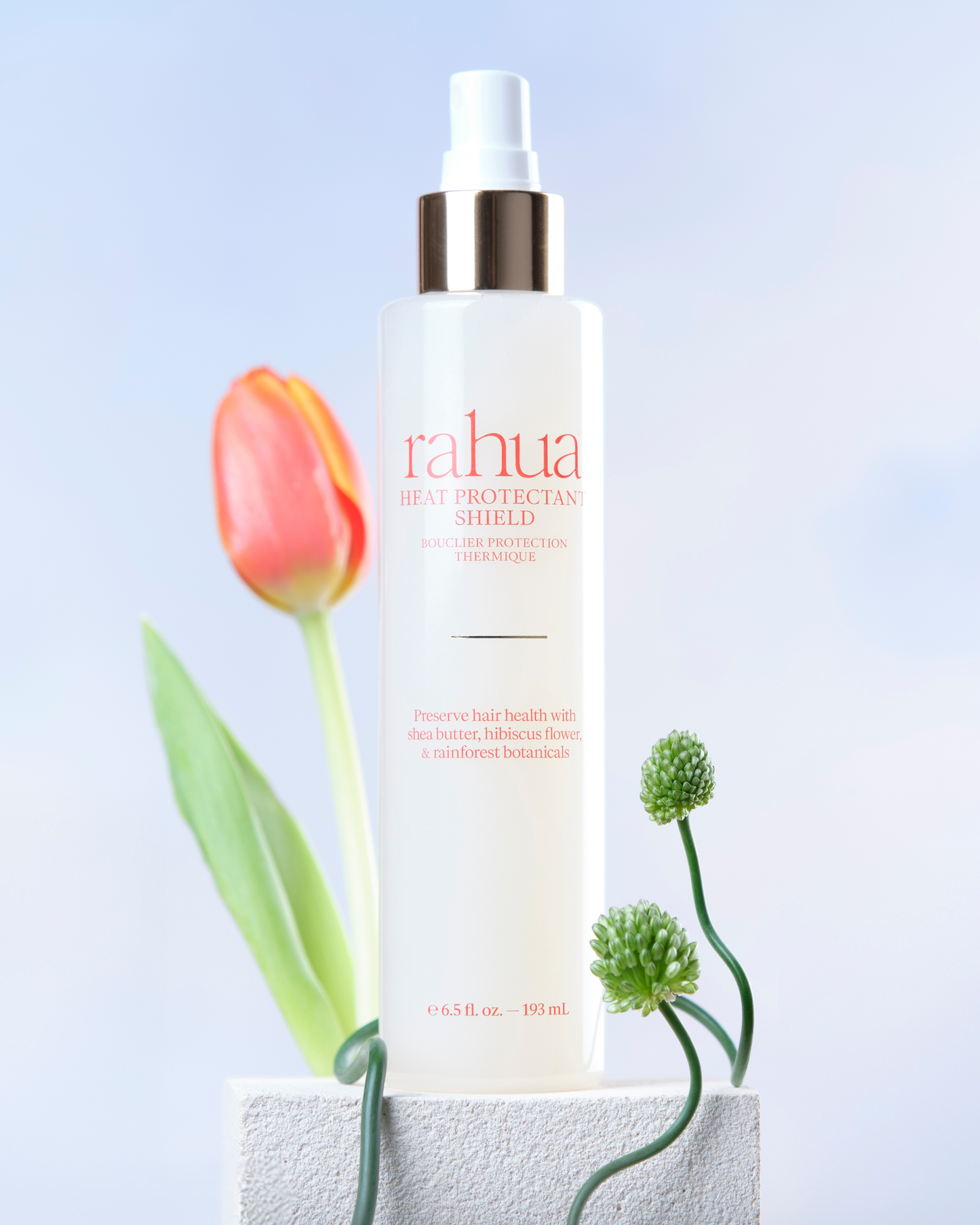 Rahua hair care product with a tulip flower on a light blue background|variant:65-oz