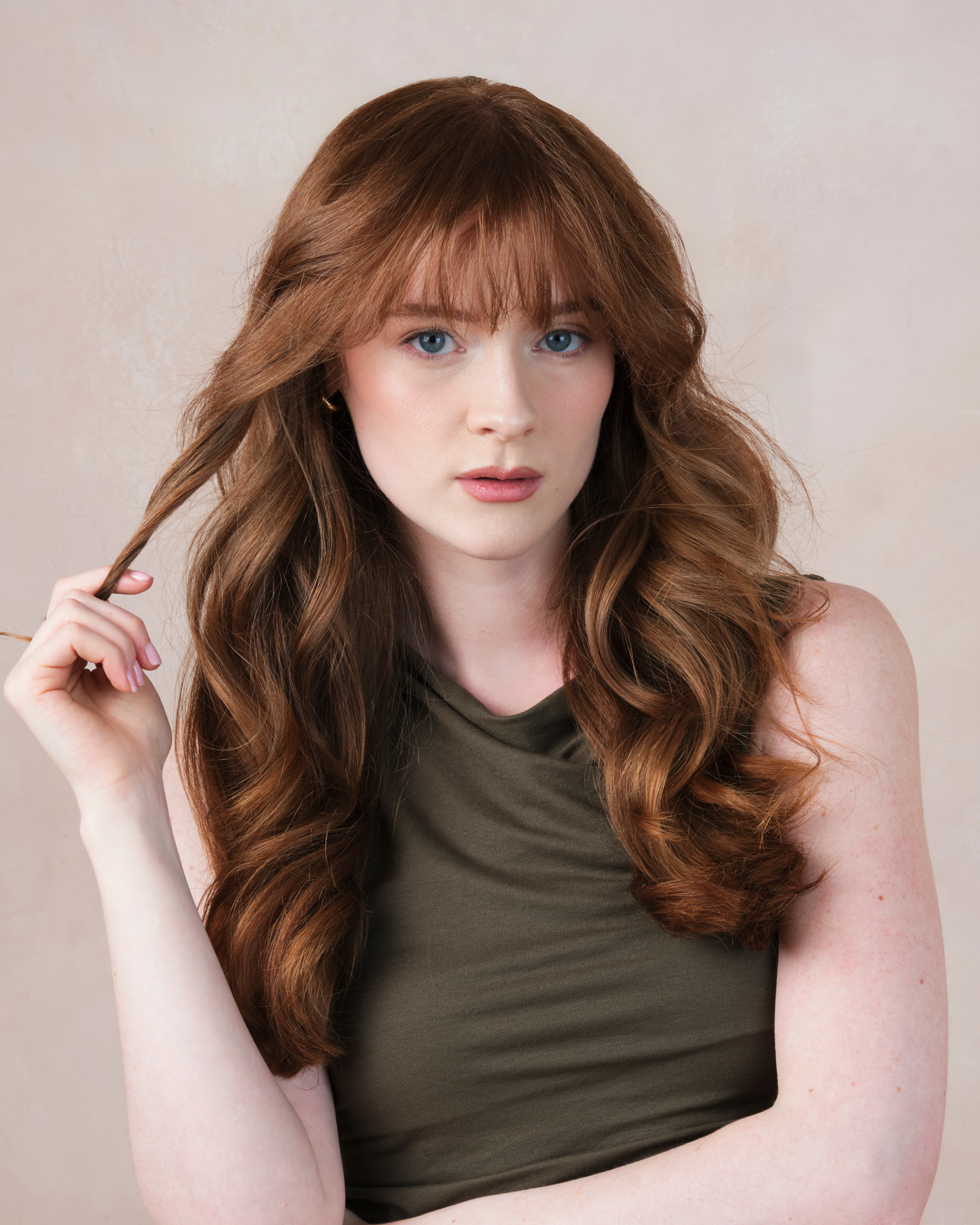 Woman with long wavy hair wearing a green top against a beige background|variant:65-oz