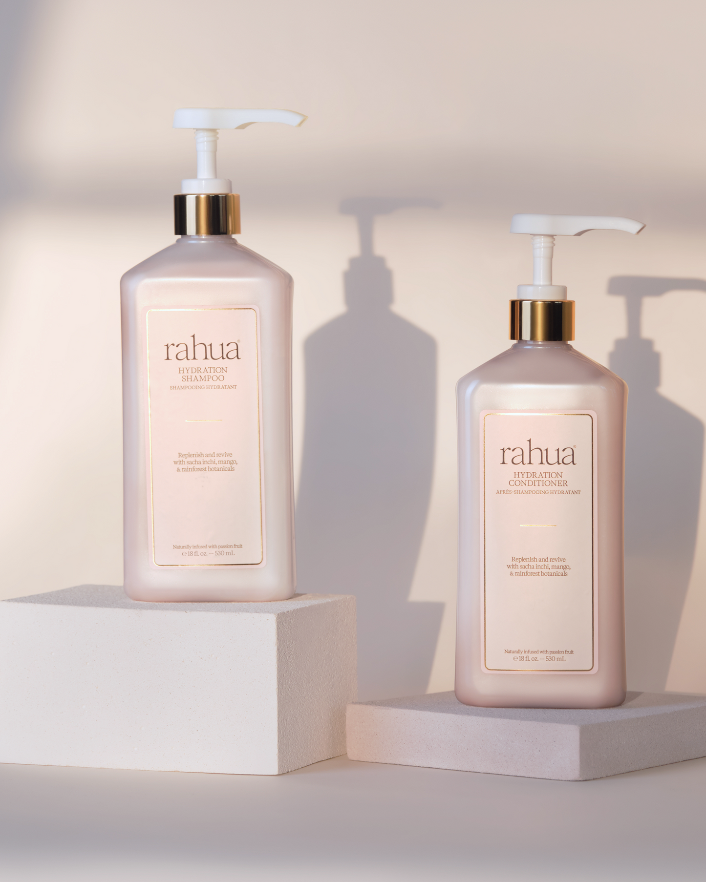 Two Rahua hair care products on white stands with a neutral background|variant:16-oz,18-oz