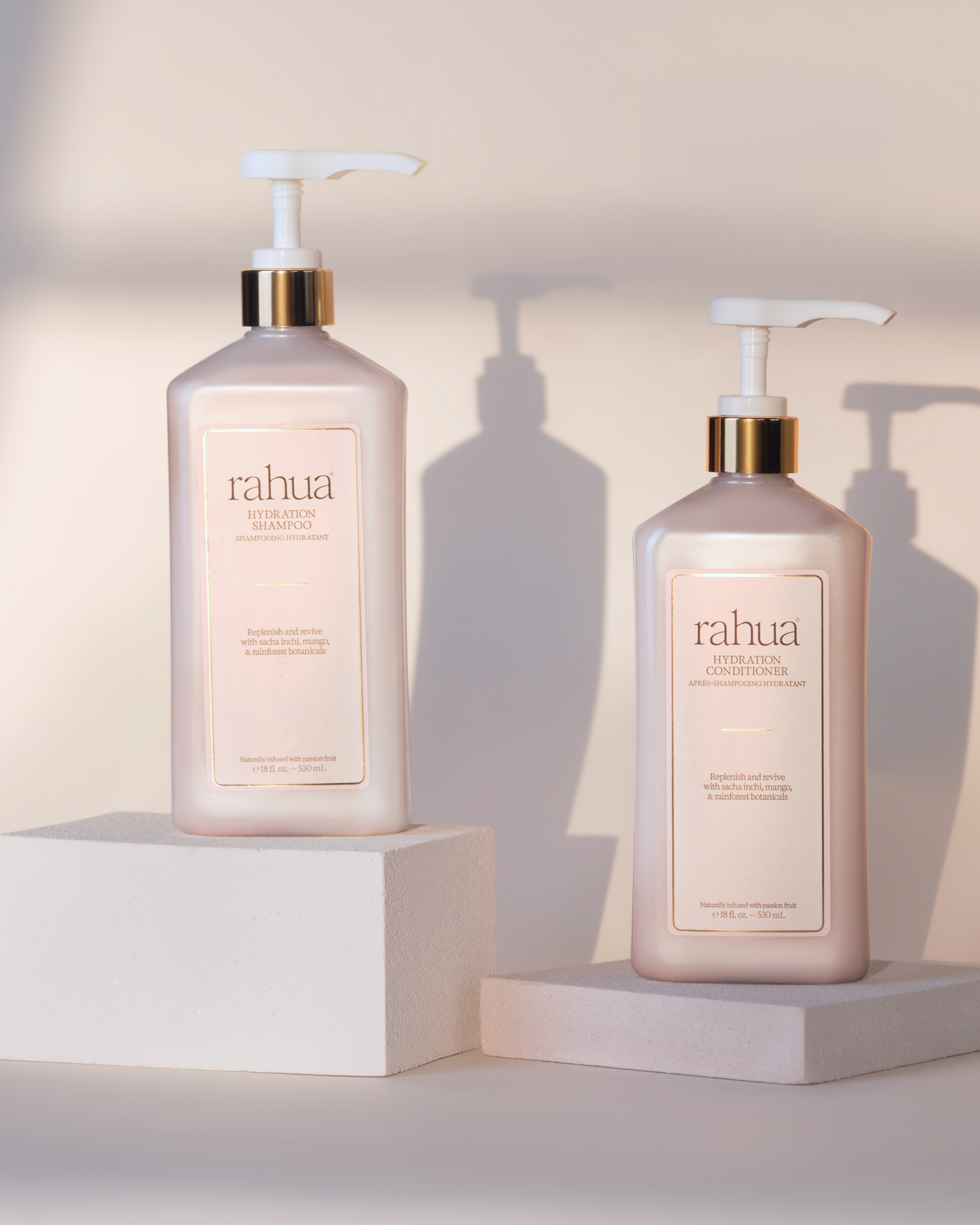Two Rahua hair care products on white stands with a neutral background|variant:16-oz,18-oz