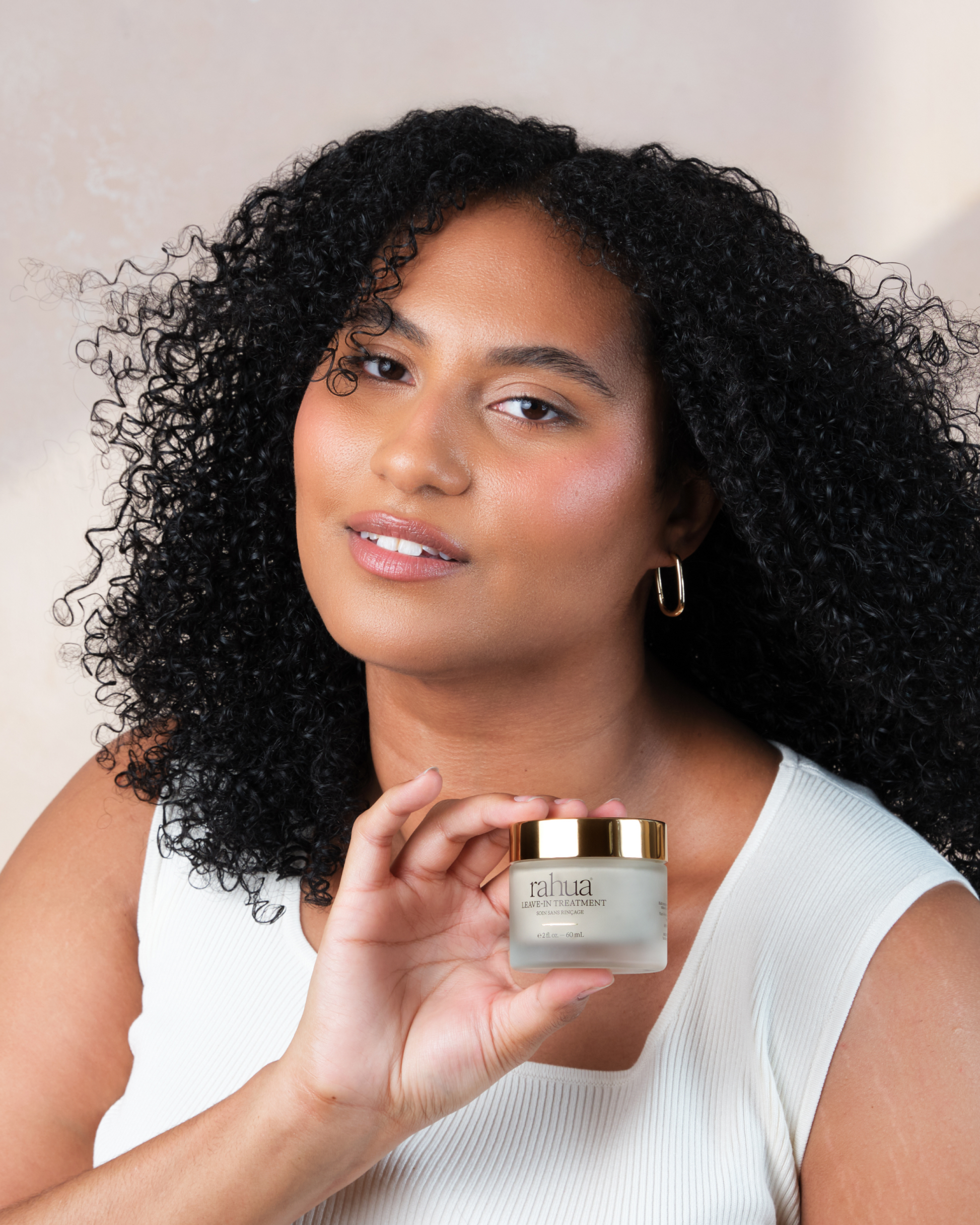 Woman holding a jar of nahua skincare product against a neutral background