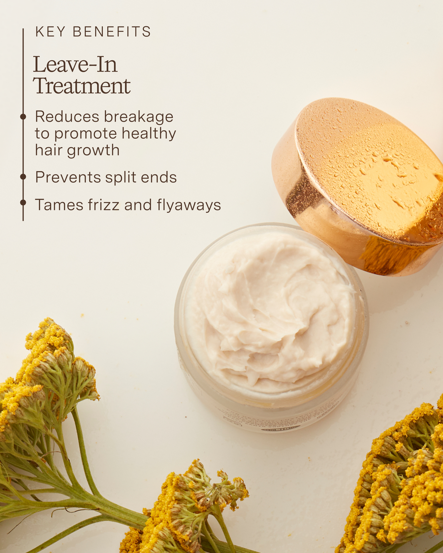 Jar of leave-in treatment cream with a wooden applicator and yellow flowers on a light background