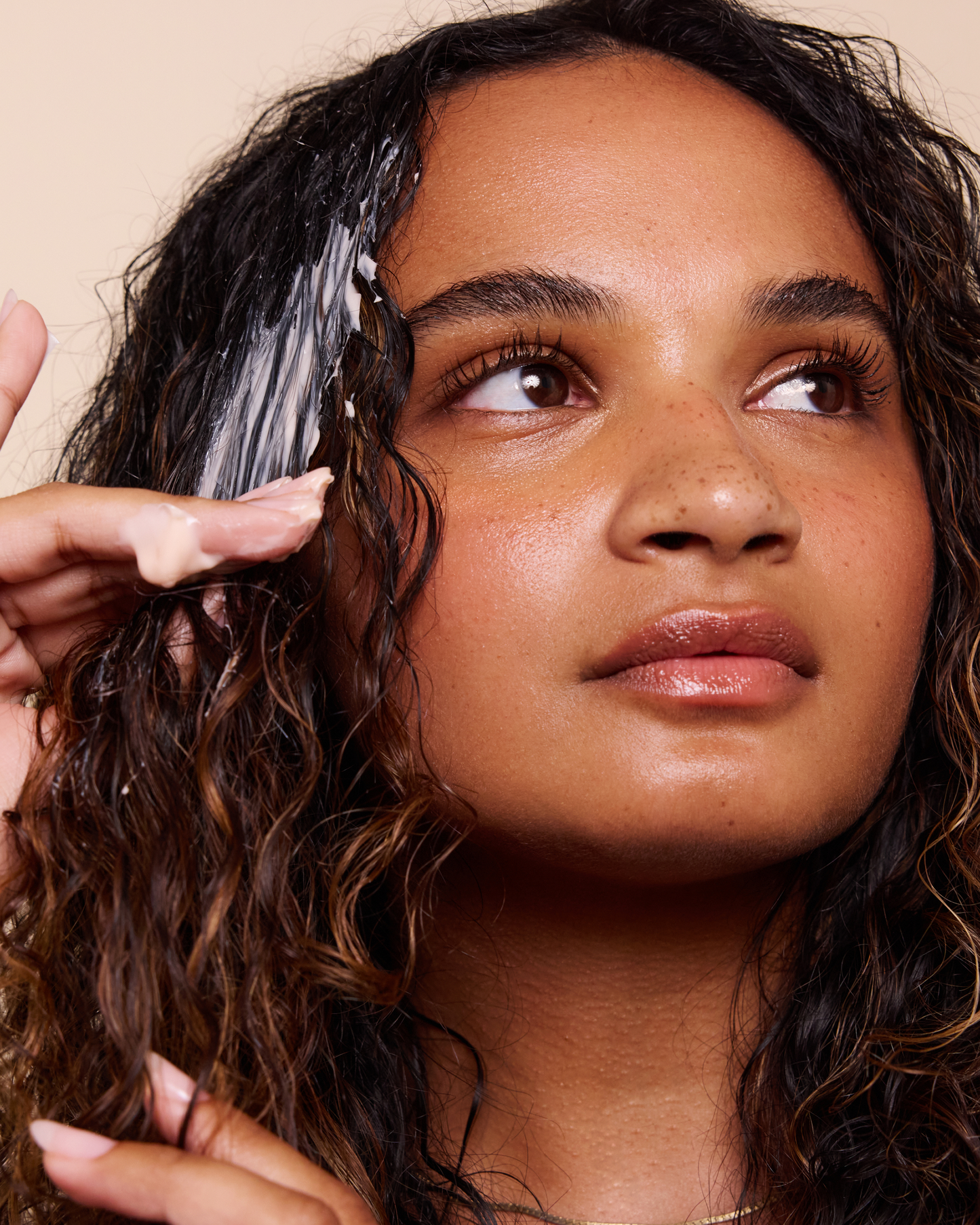 Woman with wet hair applying a product, close-up on face and hair.