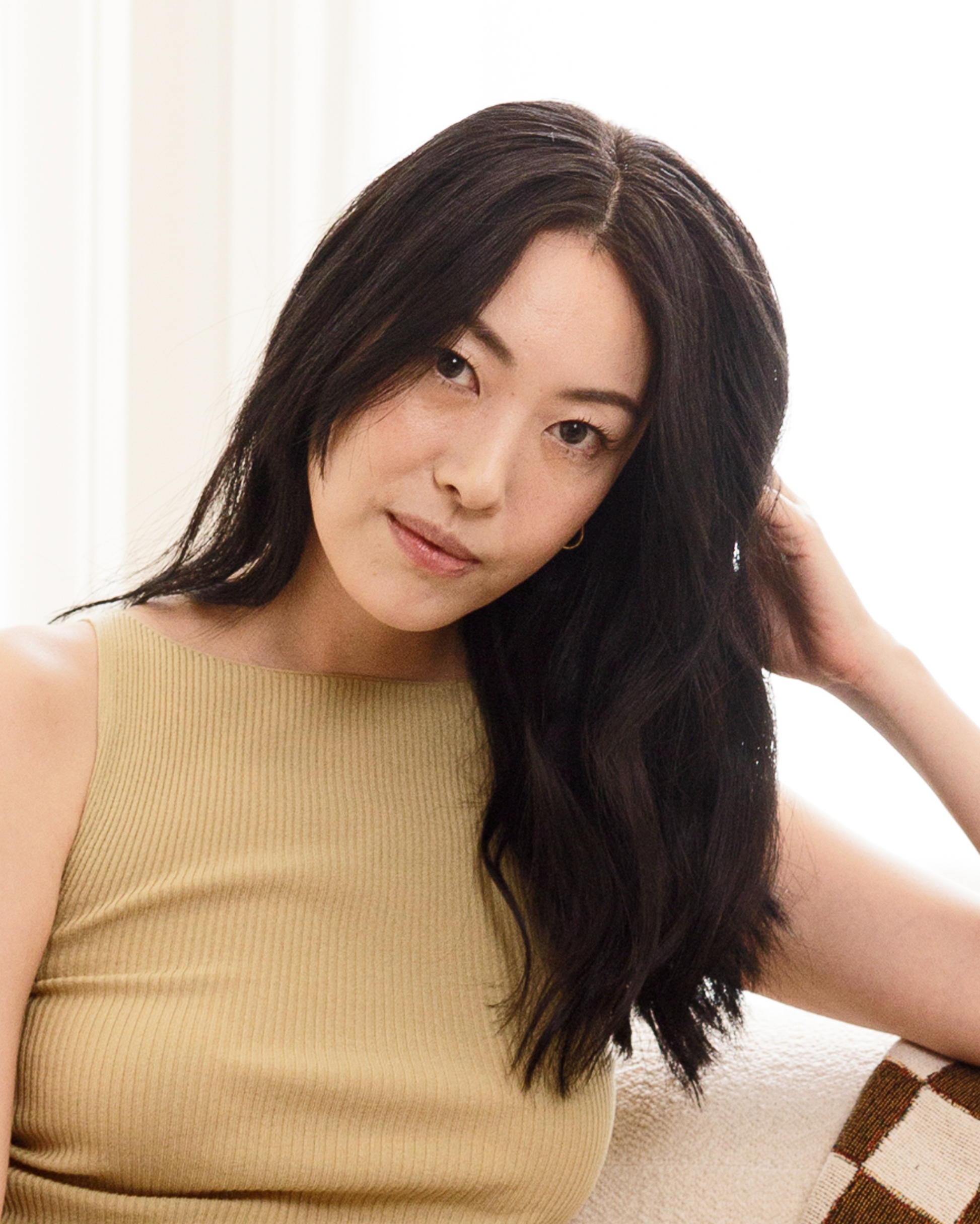 Woman with long dark hair wearing a beige sleeveless top against a neutral background|variant:93-oz