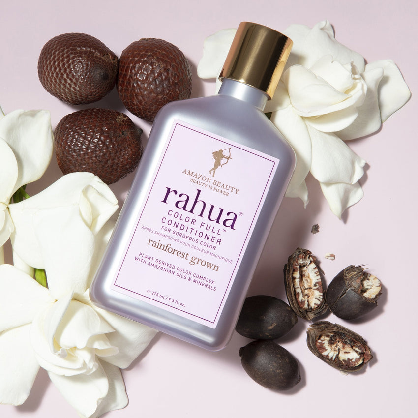 A bottle of Rahua Color Full Conditioner with a purple label and a gold cap, set against a purple background with morete, rahua and gardenia|variant:93-oz